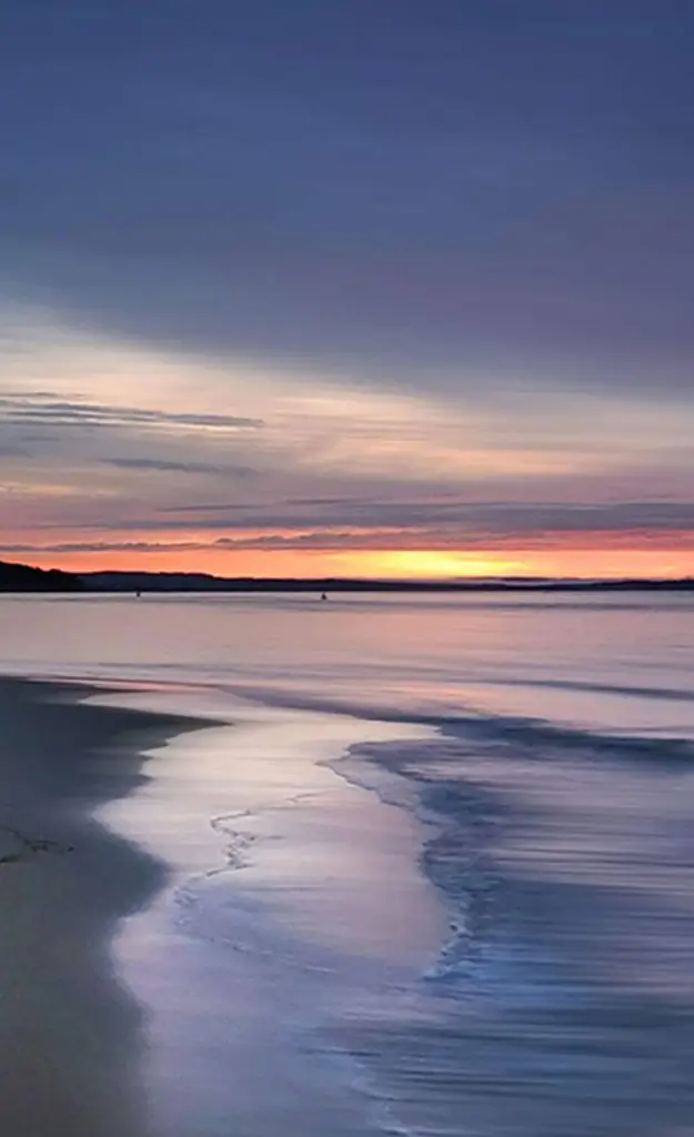 Sunset over the water at Inverloch, with waves washing over the sand